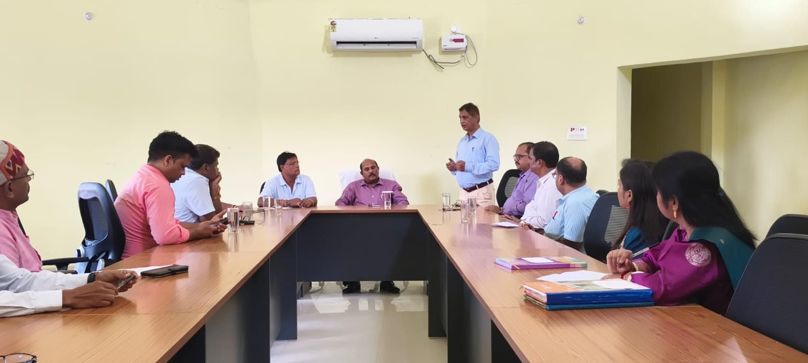 A meeting around a U-shaped table in a college conference room